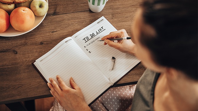 Vrouw schrijft op haar to-do-lijstje dat ze een to-do-lijstje moet maken