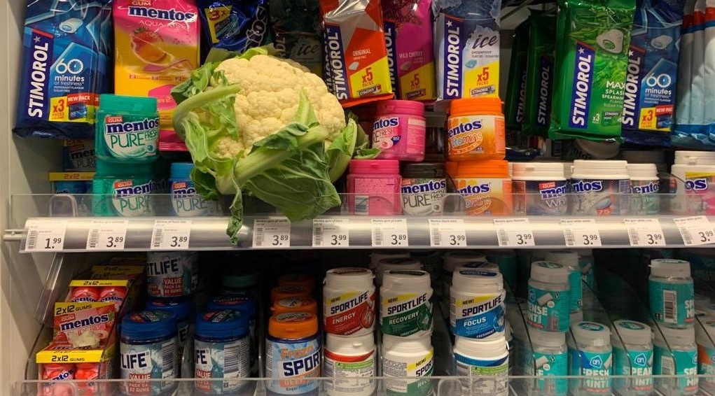 Man legt bloemkool netjes terug in het schap bij de kauwgom
