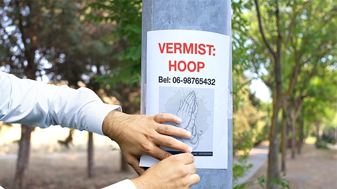 Man hangt op straat posters aan lantaarnpalen voor zijn vermiste hoop