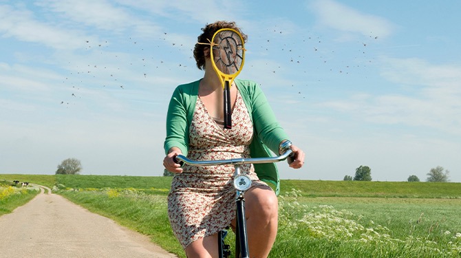 Marjan bindt elektrische vliegenmepper aan gezicht tegen vliegjes op de fiets